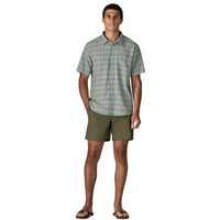 Light green plaid short-sleeve button-up shirt worn with olive green shorts, full body view