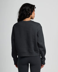 Dark fleece crew neck sweatshirt shown from back view on model
