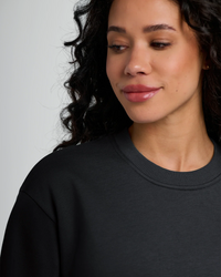 Woman wearing black fleece crew neck sweatshirt, three-quarter view against white background