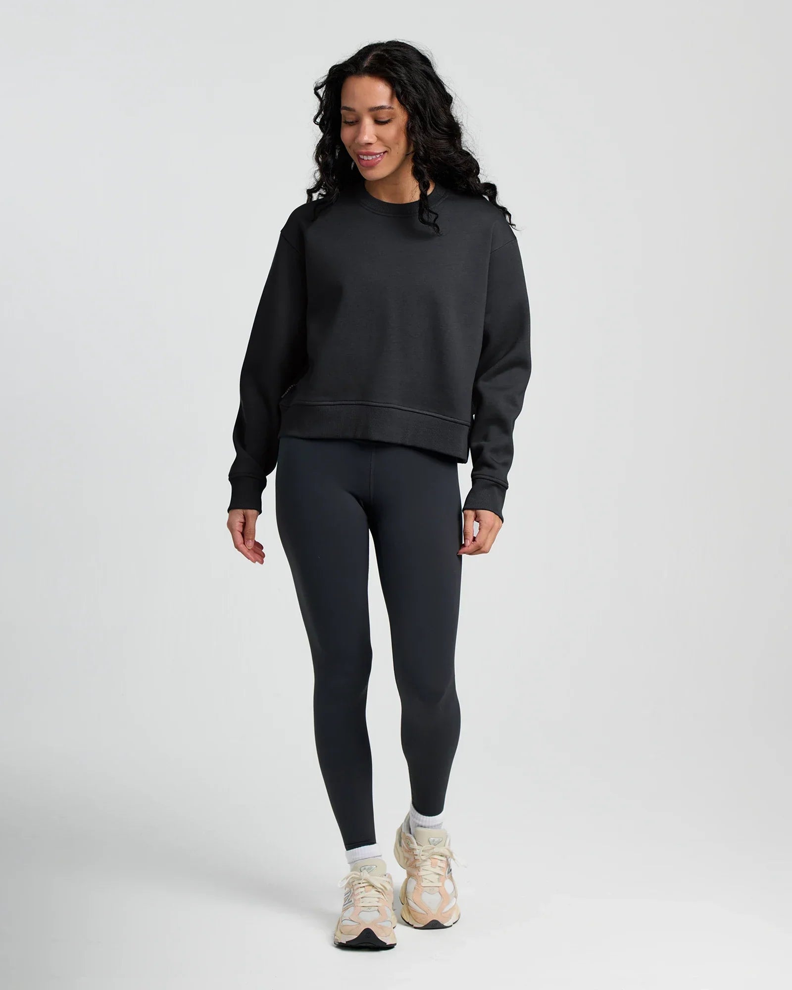 Woman wearing dark gray fleece crew neck sweatshirt with matching leggings and sneakers