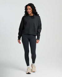Woman wearing dark gray fleece crew neck sweatshirt with matching leggings and sneakers