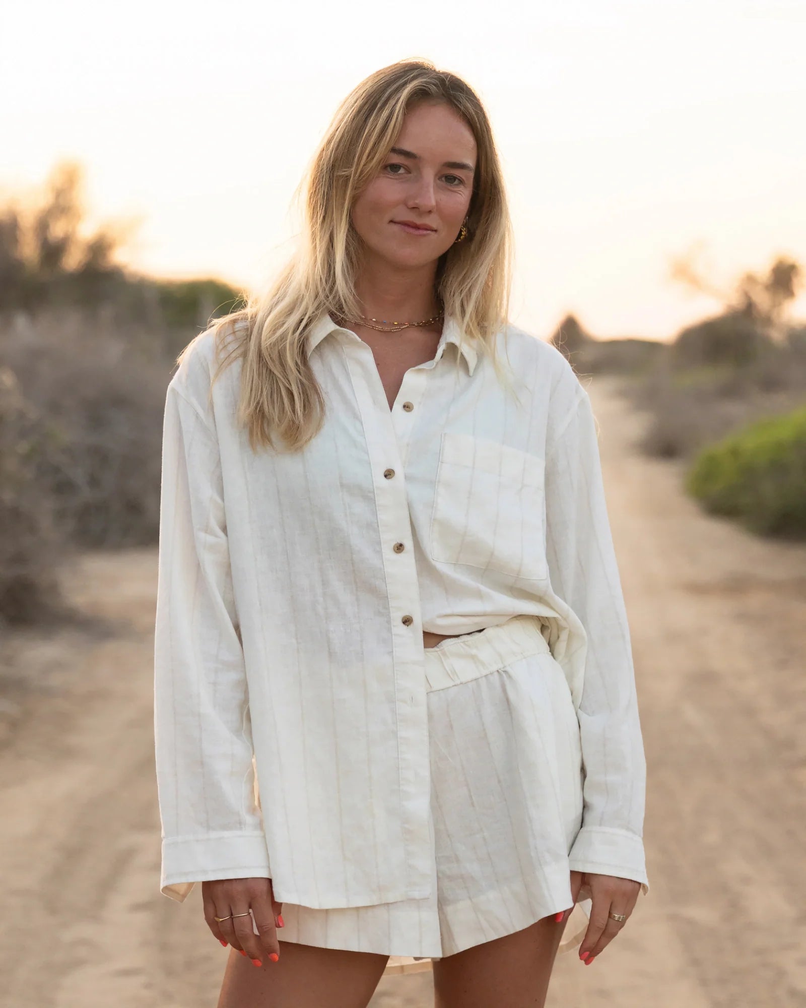 Woman wearing cream linen button-up shirt and matching shorts in outdoor setting