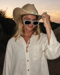 White striped button-up shirt worn casually with cowboy hat and sunglasses at sunset