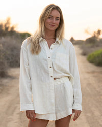 Light colored linen shorts set with button-up shirt, worn in outdoor lifestyle setting