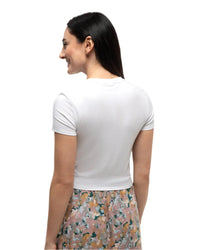 White short-sleeve fitted t-shirt shown from back angle on model with floral skirt