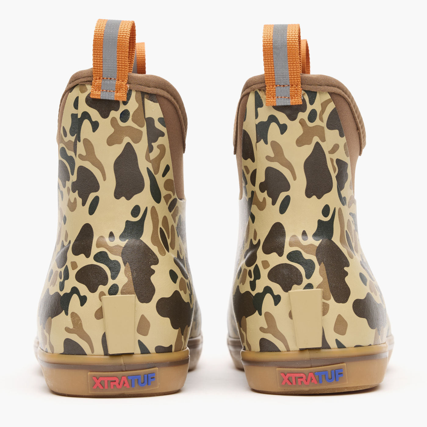 Pair of ankle-height rubber boots with camouflage pattern, orange pull tabs, and gum sole, rear view