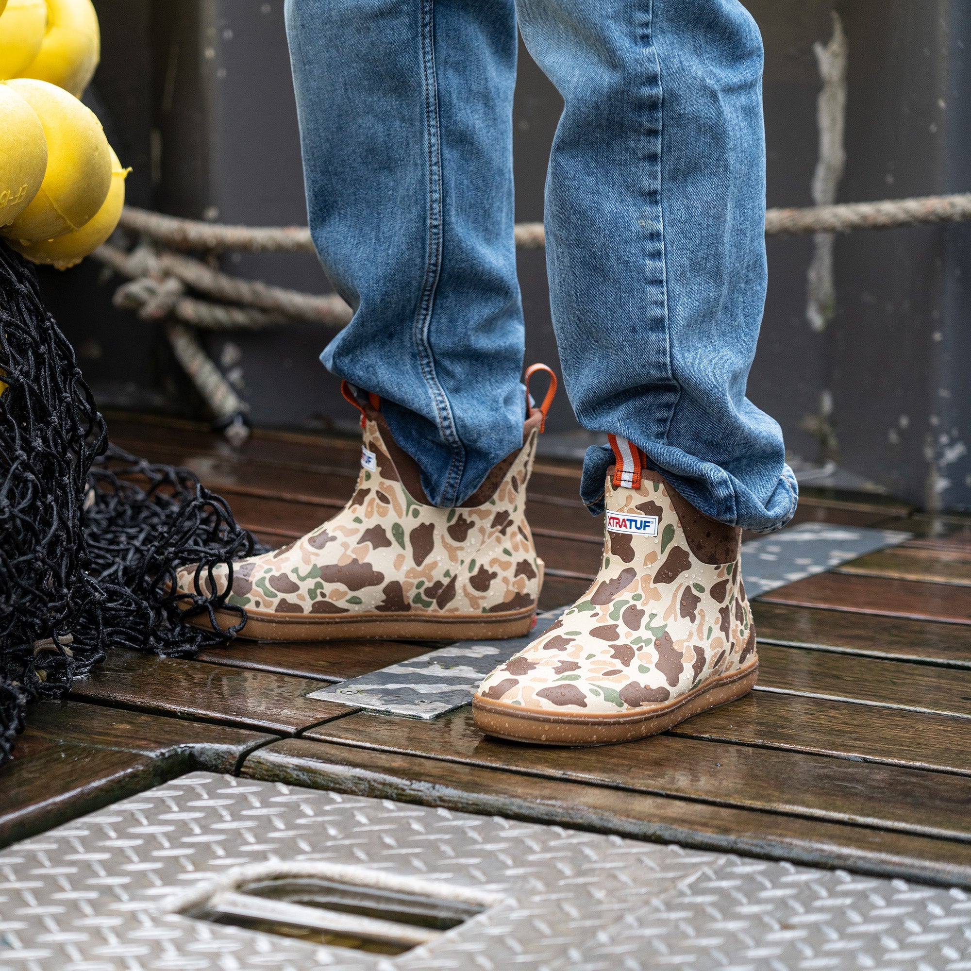 Camouflage ankle deck boots with rubber sole worn on wet boat deck, side view