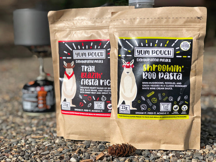 Dehydrated meal pouches in kraft paper packaging with cartoon llama mascot, outdoor setting