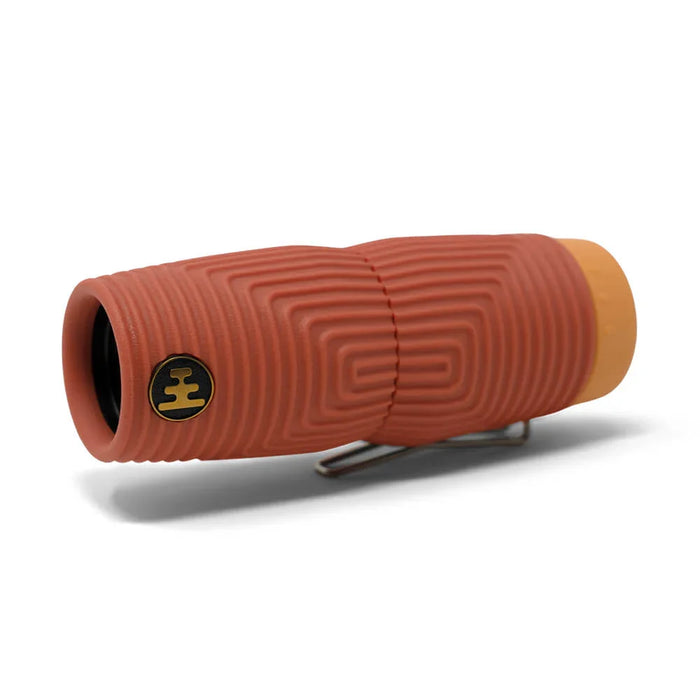 Compact monocular with textured red rubber grip, orange end cap, and metal clip, angled view