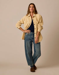 Women's oversized button-front shacket in cream, worn open over navy top with jeans, front view