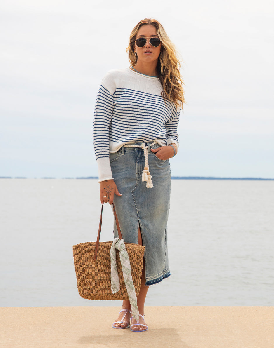 Striped sweater with white and blue horizontal stripes worn in casual beach setting