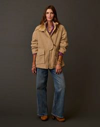 Women's oversized boucle coat in warm tan with patch pockets, worn over wide-leg jeans