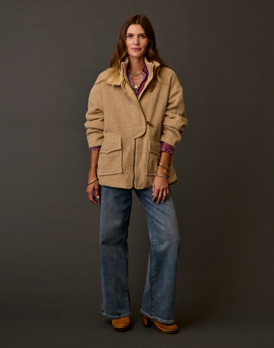 Women's oversized boucle coat in warm tan with patch pockets, worn over wide-leg jeans