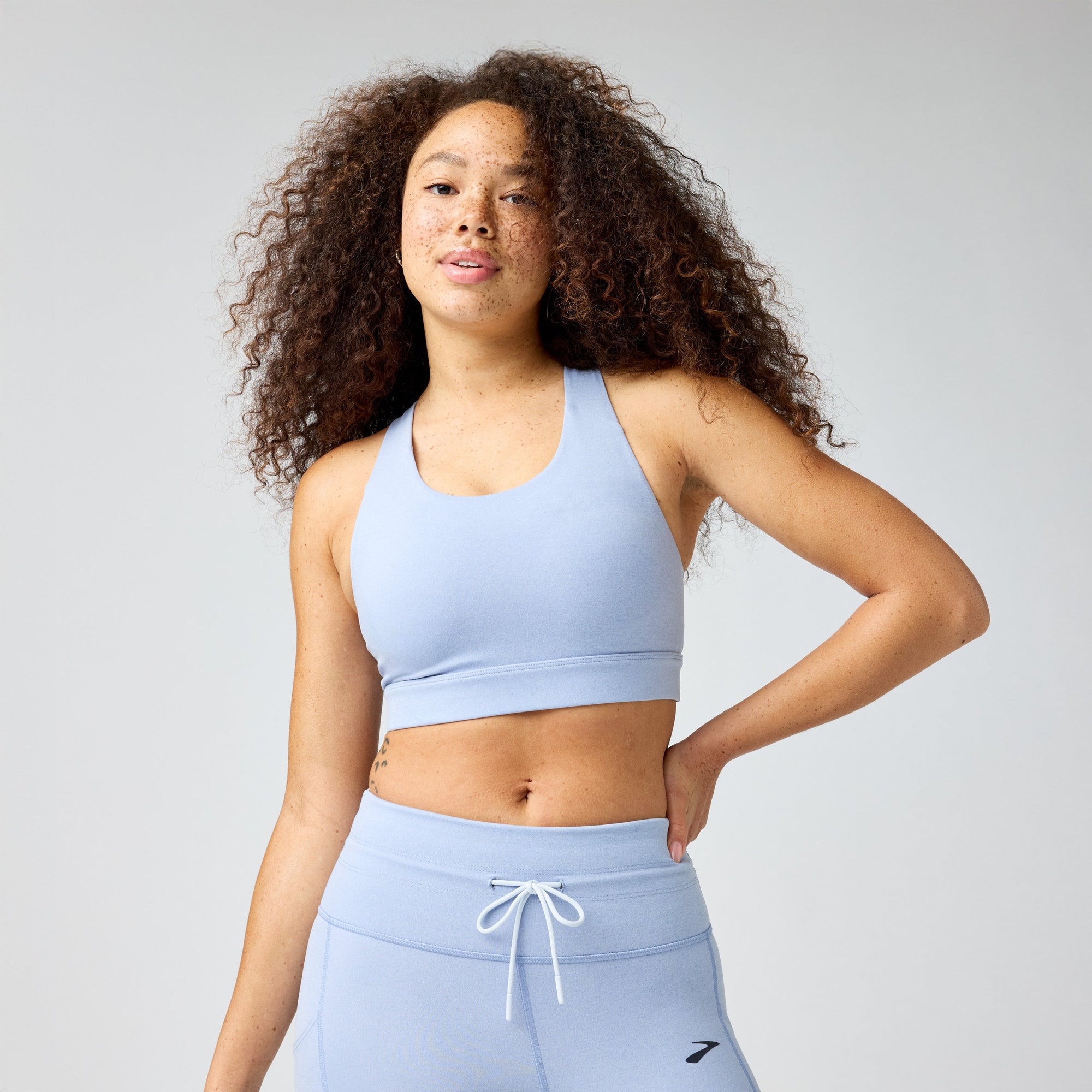 Light blue sports bra with racerback design worn by woman with curly hair