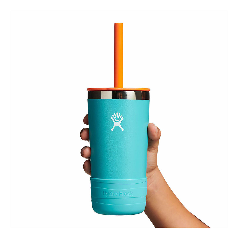 Hand holding a teal insulated kids tumbler with orange straw lid and protective rubber boot base