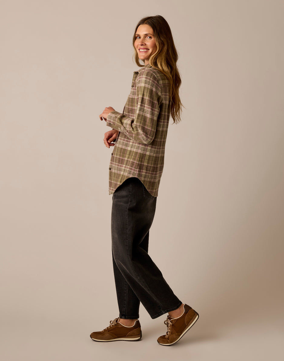 Women's plaid flannel shirt in olive and pink, side view, worn with dark jeans and sneakers