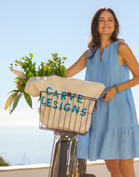 Light blue sleeveless dress with tiered ruffle hem worn by woman with bicycle