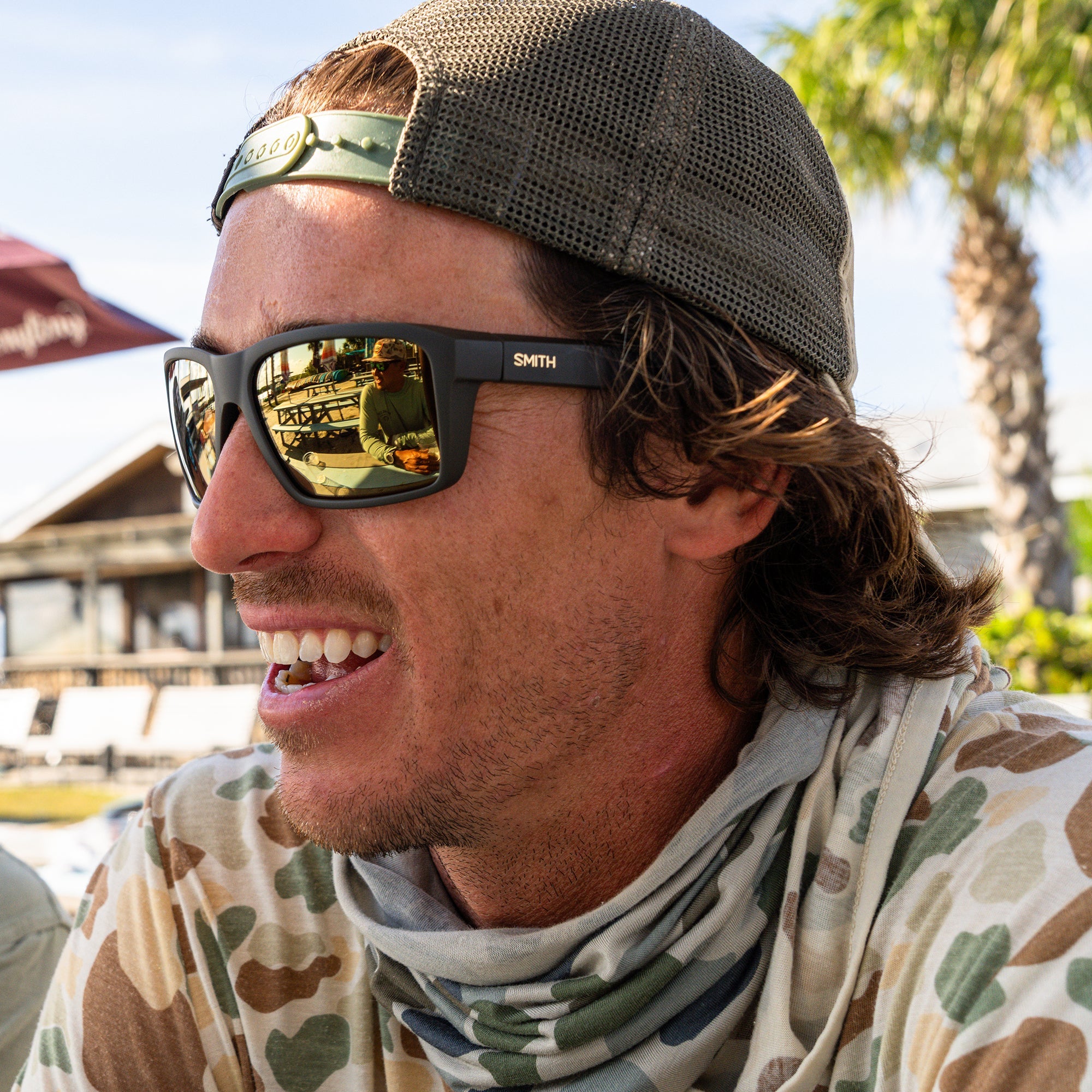 Polarized sunglasses with reflective bronze lenses worn by smiling man in outdoor setting