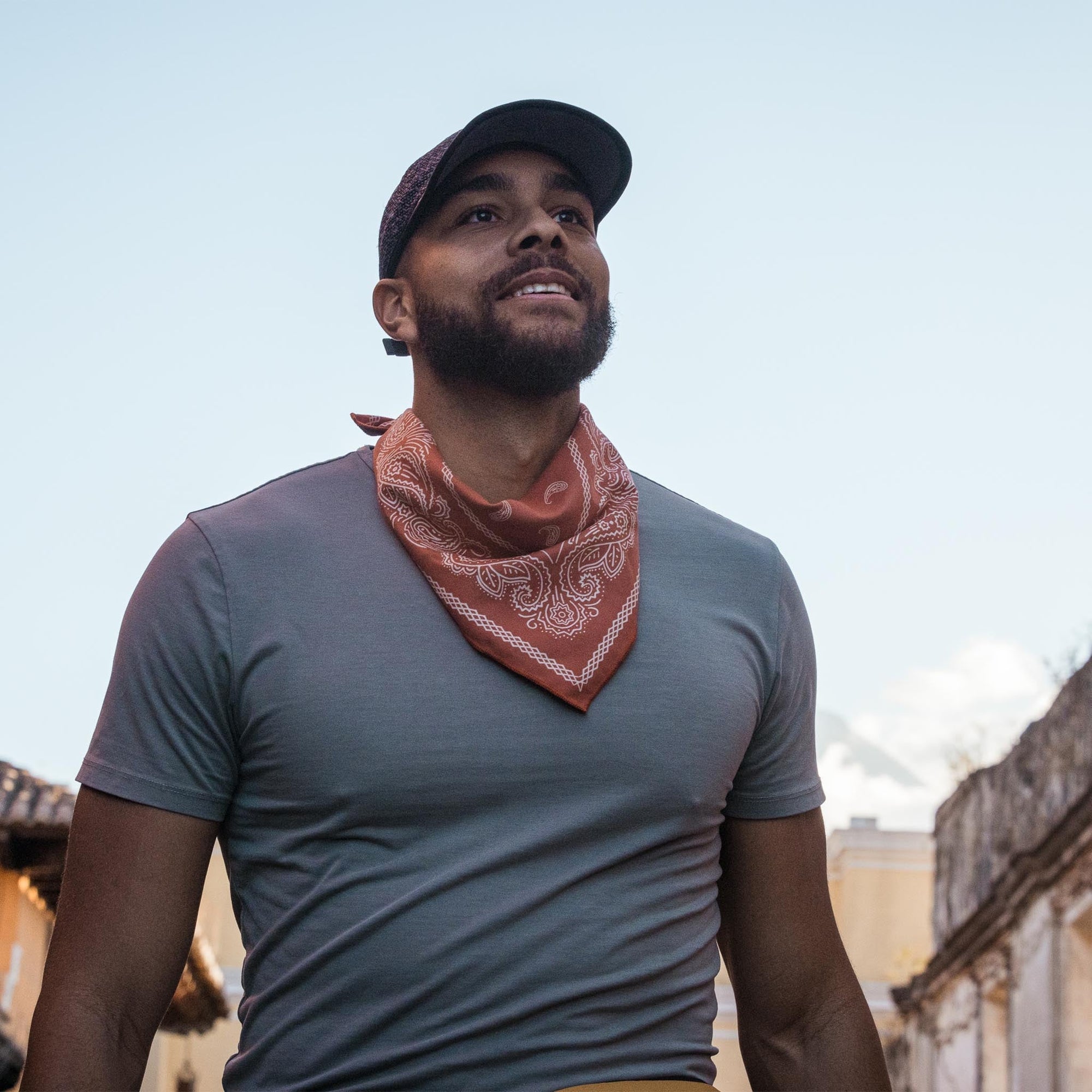 Red paisley bandana worn around neck over gray t-shirt in lifestyle setting