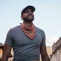 Red paisley bandana worn around neck over gray t-shirt in lifestyle setting