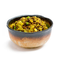 Bowl of yellow curry with lentils and diced vegetables in ceramic serving bowl