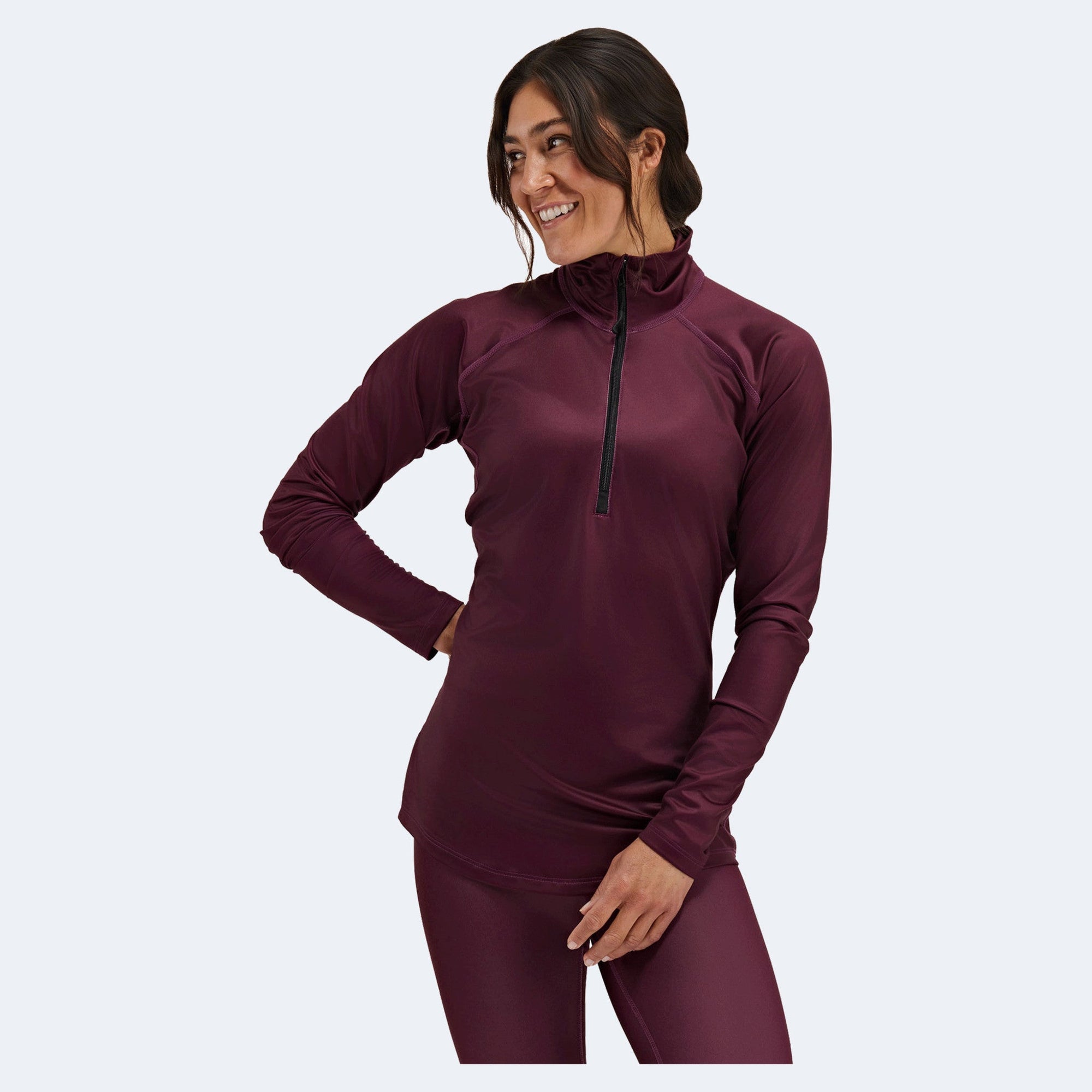 Woman wearing burgundy quarter-zip athletic top with long sleeves, studio photo