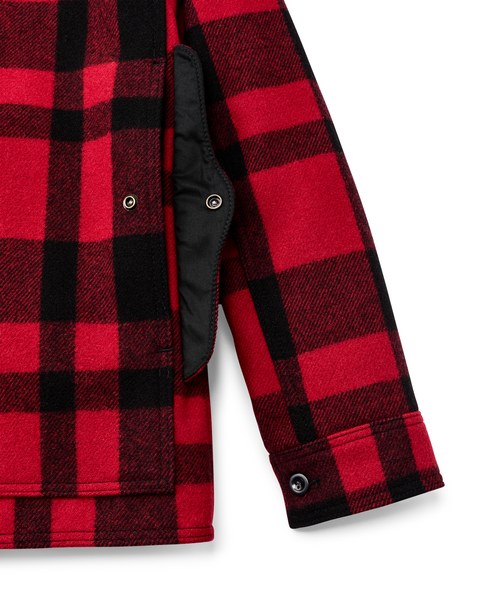 Close-up detail of red and black plaid wool cruiser jacket showing sleeve, cuff button, and black quilted lining