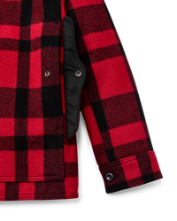 Close-up detail of red and black plaid wool cruiser jacket showing sleeve, cuff button, and black quilted lining