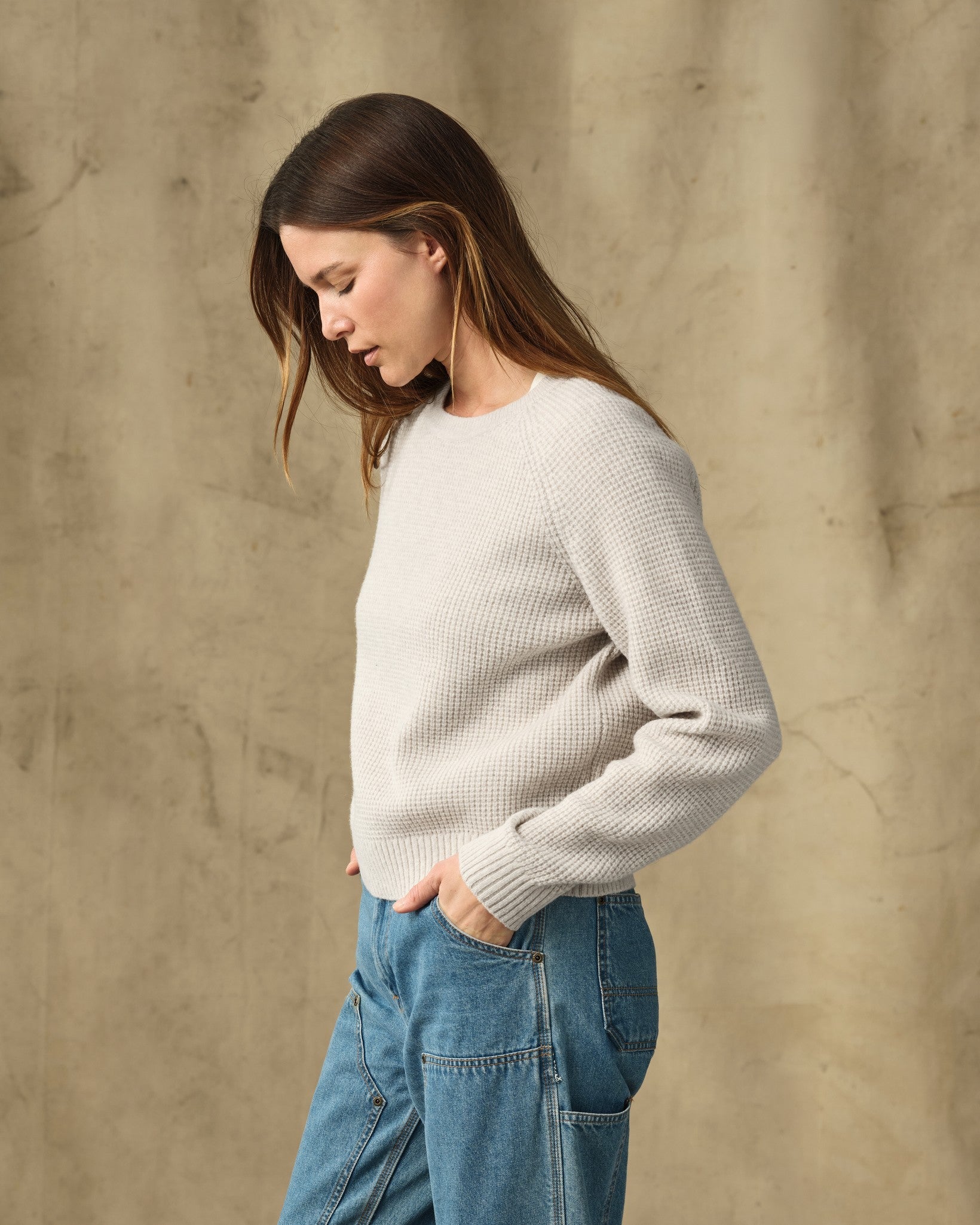 Women's waffle knit crewneck sweater in off-white, side view on model with jeans