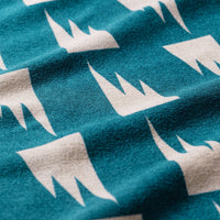 Teal towel fabric with repeating white crown pattern in close-up detail view