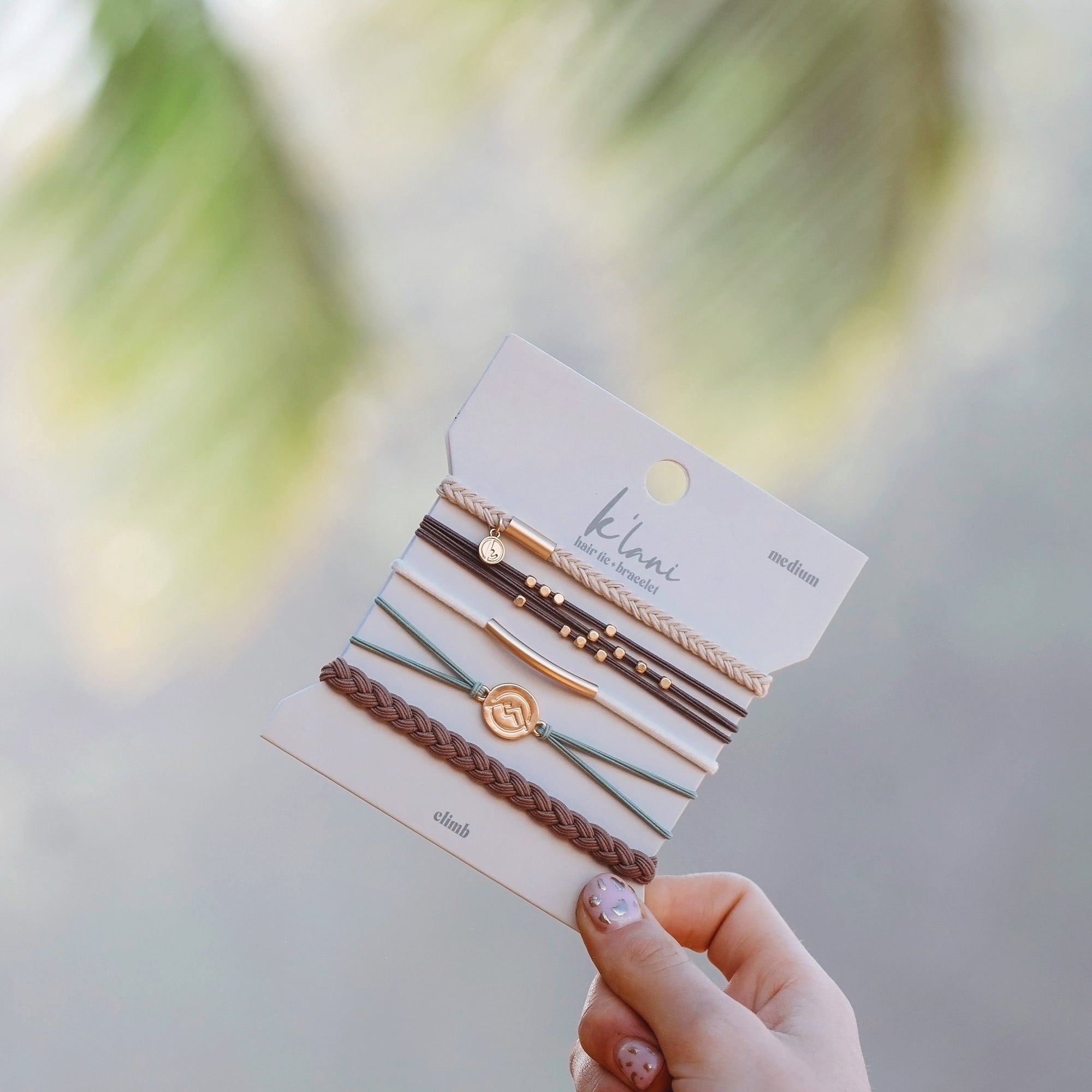 Set of five hair tie bracelets on branded card, featuring braided and cord styles with gold charms