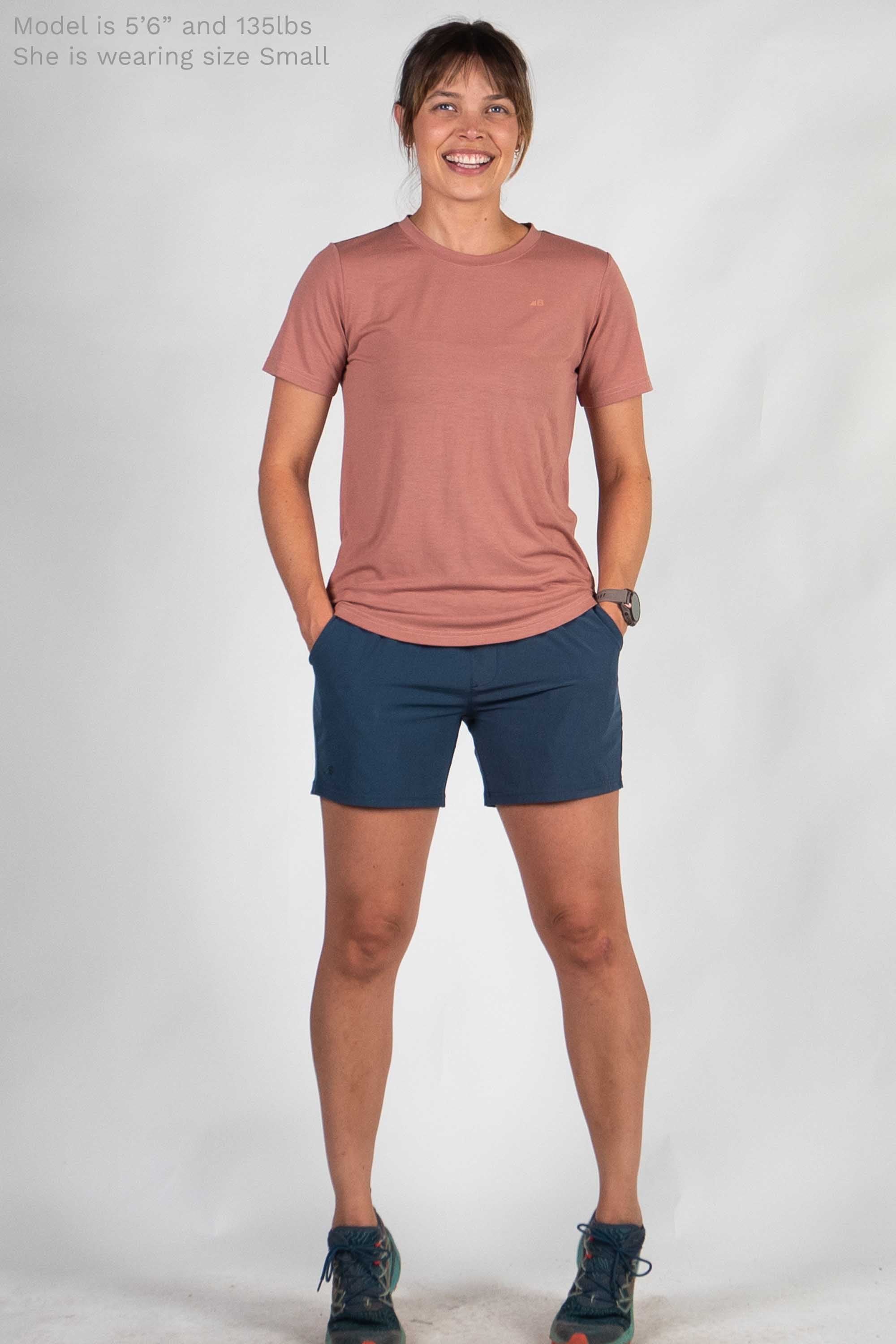 Woman wearing dusty rose short-sleeve tee and navy shorts in studio photo
