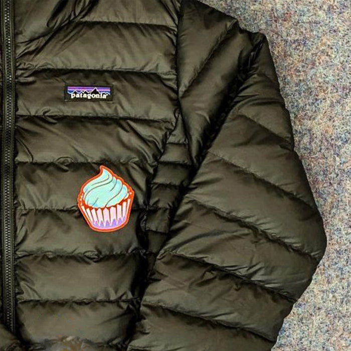 Embroidered cupcake patch with blue frosting on olive green quilted puffer jacket
