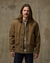 Men's canvas chore jacket in tan brown with corduroy collar and multiple pockets, front view