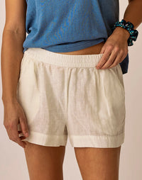 Light colored linen shorts with elastic waistband and cuffed hems on model