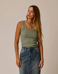 Woman wearing sage green ribbed tank top with denim skirt, studio shot