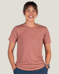 Woman wearing dusty rose short-sleeve athletic t-shirt, smiling at camera