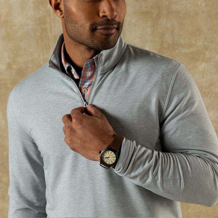Light grey quarter-zip pullover with textured fabric worn over plaid shirt