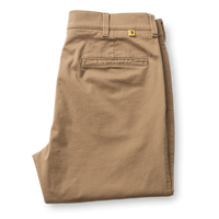 Folded classic fit chino pants in tan, showing back pocket and belt loops