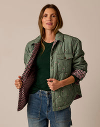 Women's reversible quilted shirt jacket in sage green with pink checkered lining, open front view
