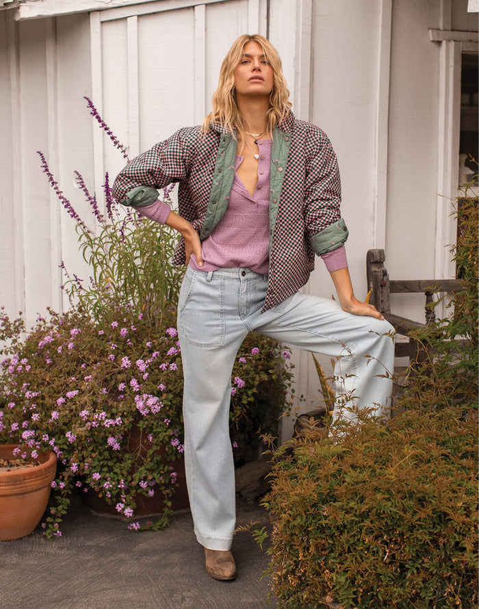 Women's reversible bomber jacket in houndstooth check pattern with green quilted lining, worn open over pink top