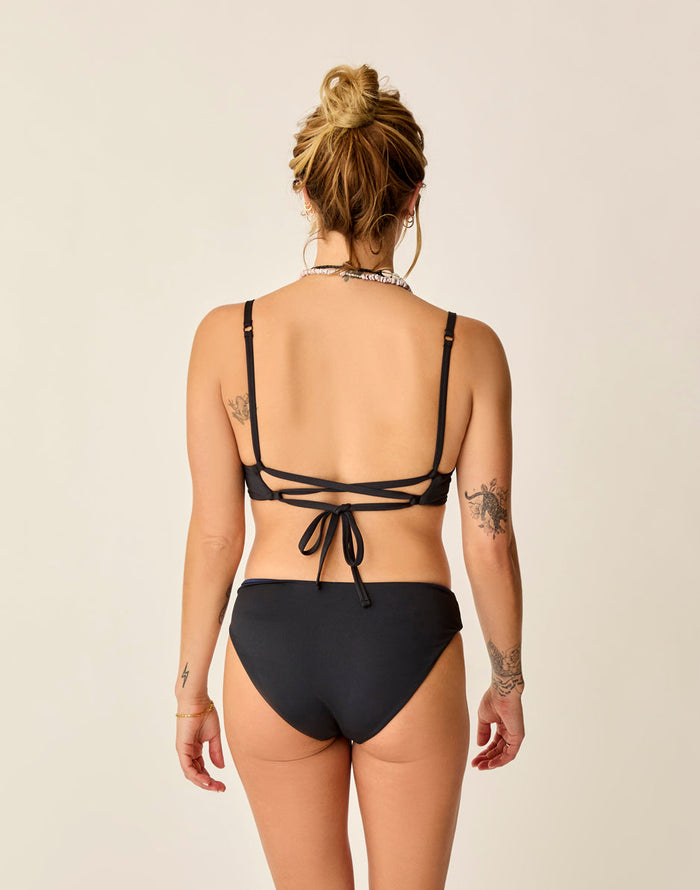 Black reversible bikini bottom shown from back on model with tattoos, full coverage cut