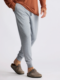 Men's grey jogger pants with drawstring waist and cuffed ankles, side view on model
