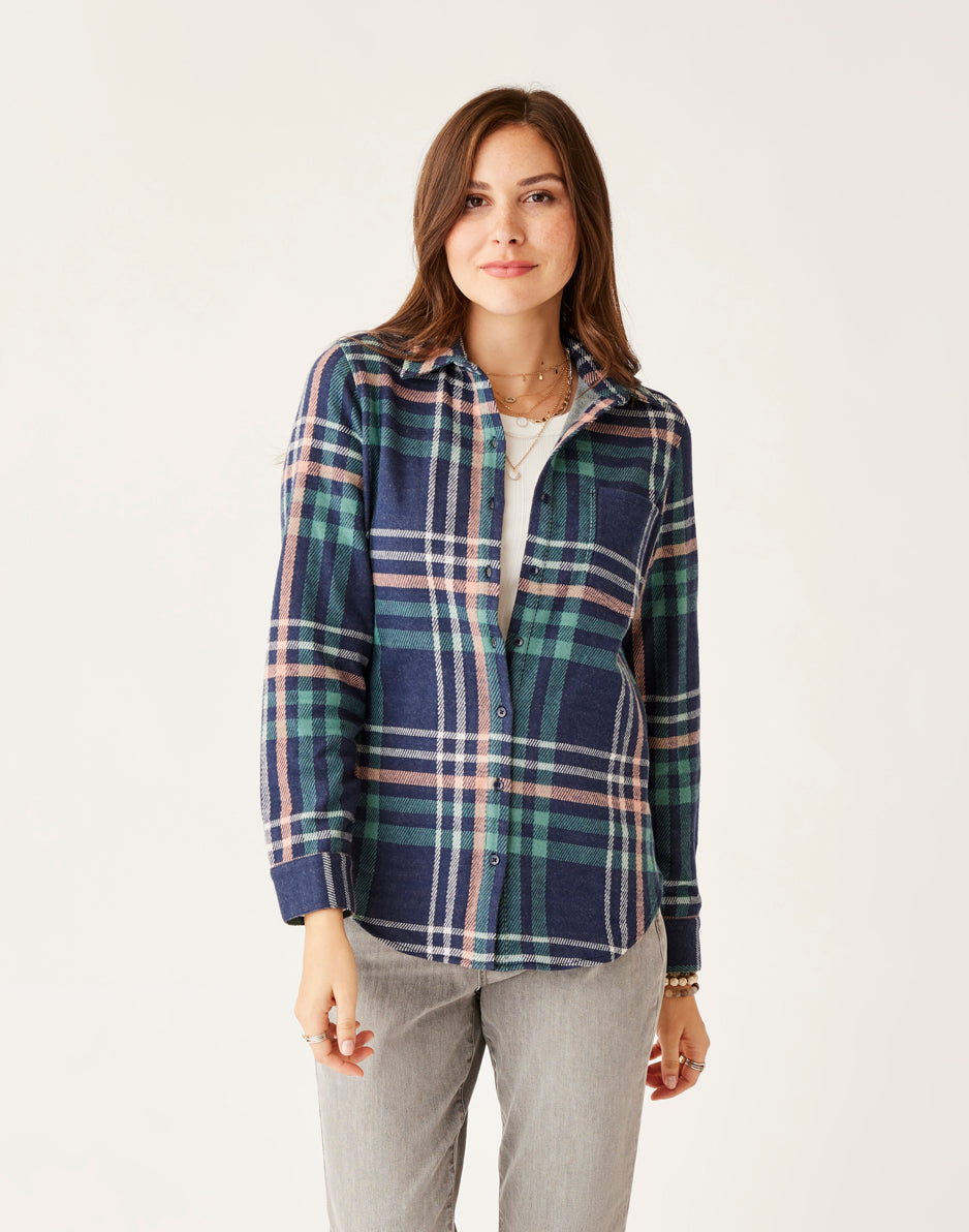 Women's plaid flannel button-up shirt in navy, green, and pink, worn open over white tee