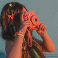 Colorful neon hair ties worn in hair and stacked bracelets on wrist, lifestyle shot