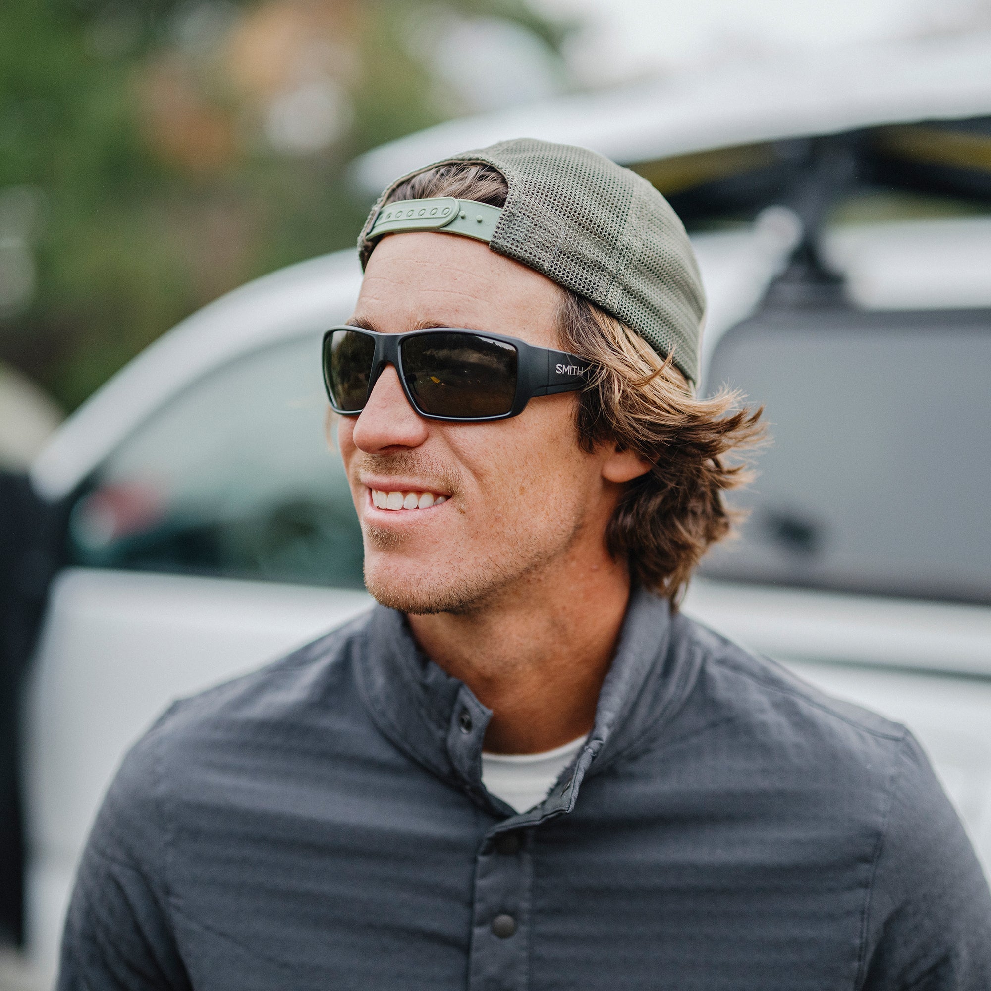 Man wearing wraparound polarized sunglasses with dark lenses in outdoor lifestyle setting