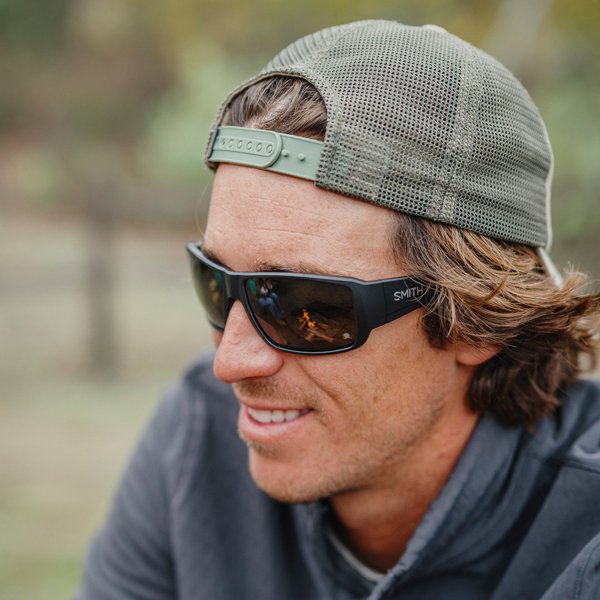 Man wearing wraparound sunglasses with dark lenses and baseball cap, outdoor lifestyle shot