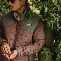 Two-tone quilted jacket with brown lower body and olive upper panel, worn by man outdoors