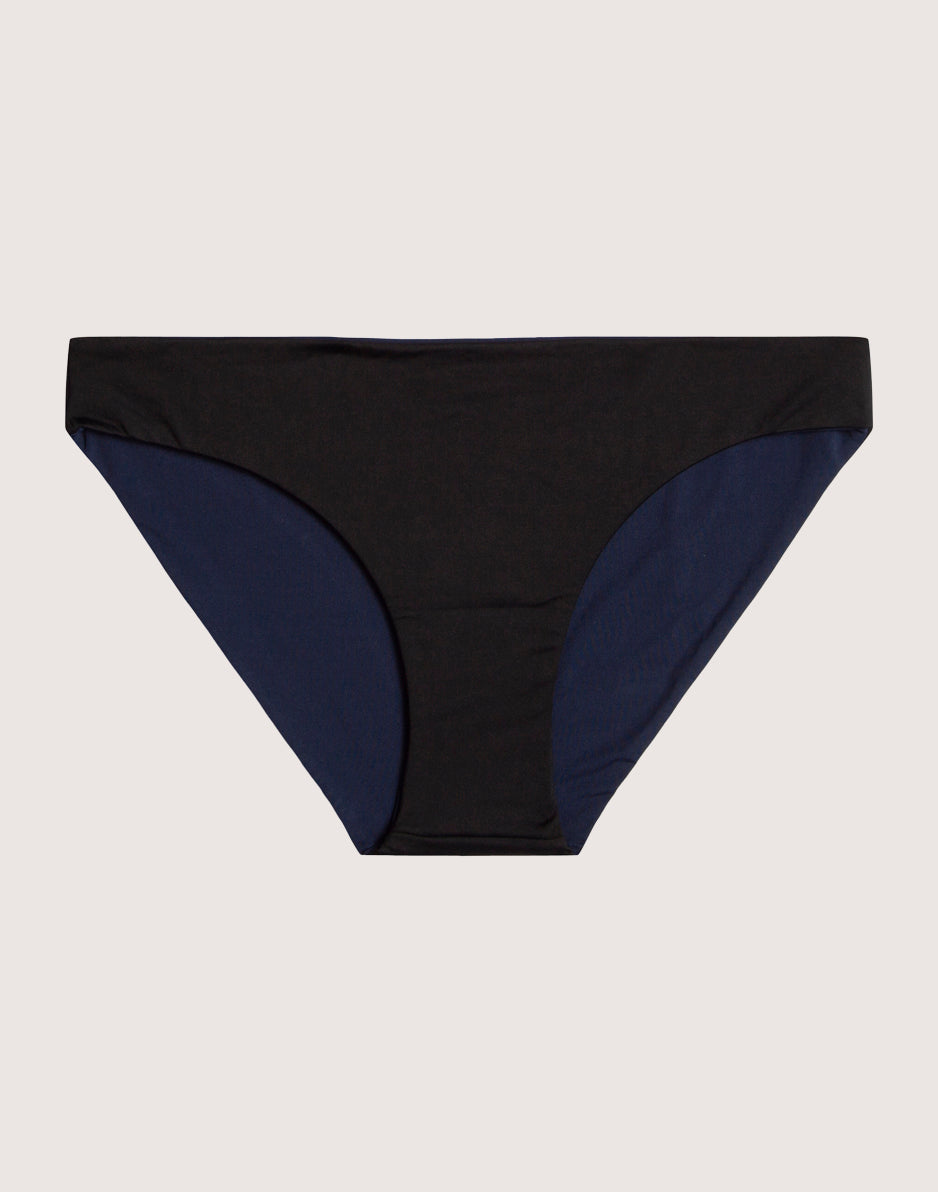 Reversible bikini bottom with black front panel and navy blue side panels, flat lay view