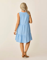 Light blue sleeveless tiered dress shown from back, knee-length with ruffled hem